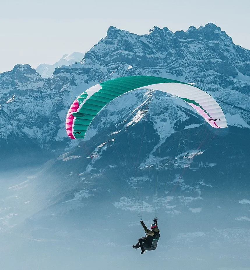 Niviuk Koyot 6 et Koyot 6 P : L'EN-A fait sa mue Koyot 6 couleur Guava en vol avec les alpes enneigée en fond